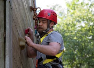 Camper climbing the climbing wall wearing helmet and harness
